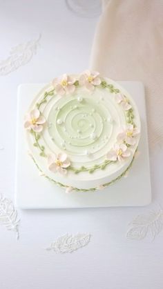 a white cake with flowers on it sitting on top of a table next to a napkin