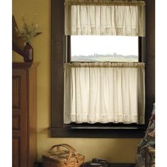 a window with white curtains and a basket in front of it