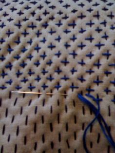 the blue thread has been hooked up to the white fabric with black crosses on it