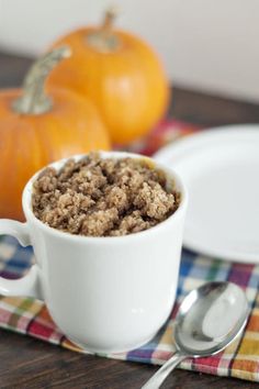 a bowl of oatmeal sitting on top of a table next to two orange pumpkins