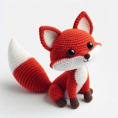 a crocheted red fox sitting on top of a white table