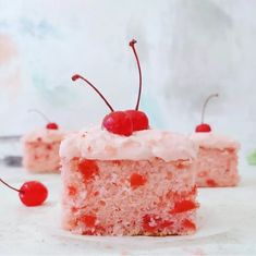 a piece of cake with pink frosting and cherries sitting on top of it