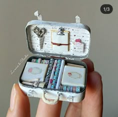 an open suitcase with many items in it sitting on someone's fingernails