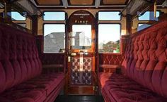 the inside of a train car with red velvet seats and wood trimmings on it