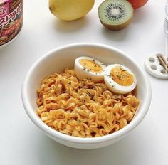 a bowl filled with noodles and two hard boiled eggs on top of it next to some fruit