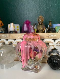 there is a vase with pink icing on it next to other decorations and glass items