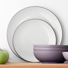 plates, bowls and an apple sit on a shelf