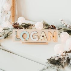 a wooden sign sitting on top of a white table next to christmas decorations and lights