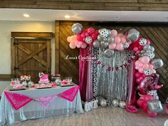 a table topped with lots of pink and silver balloons