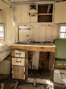 an old run down kitchen with broken cabinets