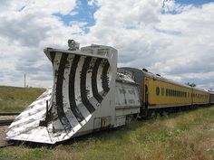 a train that is sitting on the tracks in the grass and has been turned upside down