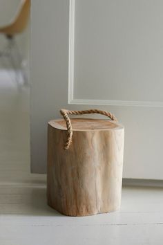 a wooden stool with rope on top of it next to a white wall and door