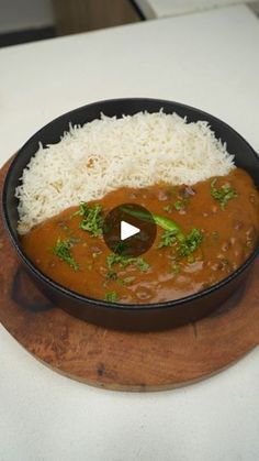 a bowl filled with rice and curry on top of a wooden plate