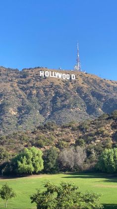 the hollywood sign is on top of a hill in front of some trees and mountains