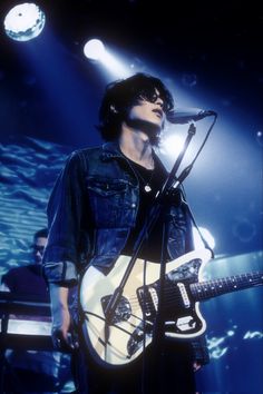 a man standing in front of a microphone and guitar