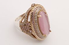 an image of a pink stone ring on a white surface with gold trimmings