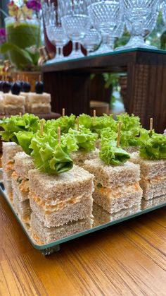 sandwiches with lettuce and olives are arranged on a platter in front of wine glasses