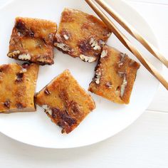 some food on a white plate with chopsticks