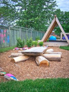 a wooden table sitting in the middle of a yard next to a tree stump structure