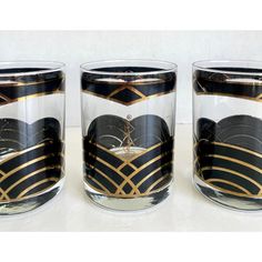 three glasses with black and gold designs on them