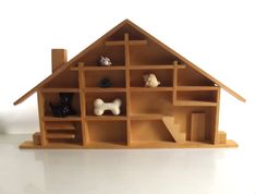 a doll house made out of bookshelves on a white surface with a dog figurine in the window