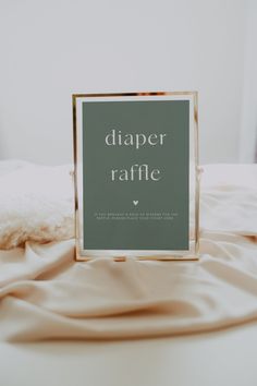 a sign that reads diaper raffle on top of a bed covered in sheets