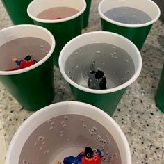 several plastic cups filled with water and small toy figurines on top of them