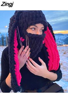 a woman wearing a knitted scarf and holding her hands in front of her face