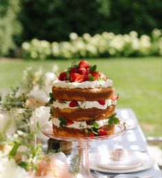 a cake sitting on top of a table covered in strawberries and other food items