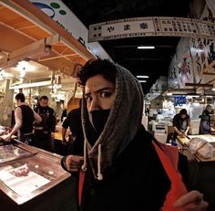 a man wearing a scarf standing in front of a counter with food items on it