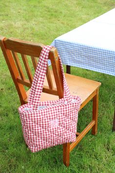 two wooden chairs sitting on top of a grass covered field next to a picnic table