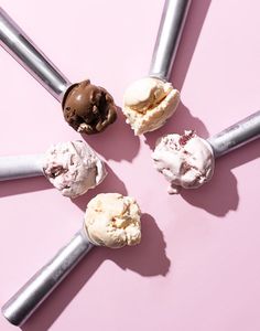 six ice cream cones arranged in a circle on a pink surface with the top one half eaten