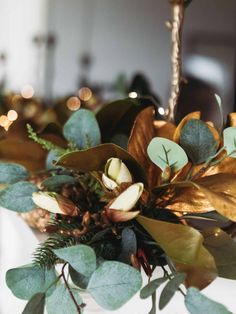 a vase filled with flowers and greenery on top of a table