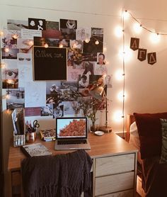 a laptop computer sitting on top of a wooden desk in front of a wall covered with pictures