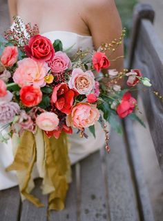 a woman holding a bouquet of flowers on top of a wooden bench