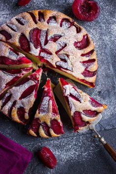 a cake with slices cut out and covered in powdered sugar, raspberries