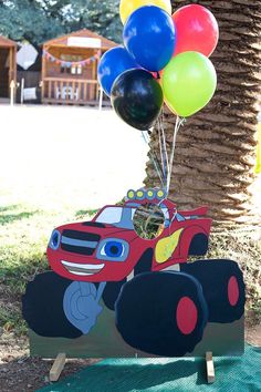 a red monster truck with balloons in the shape of cars is on display at a children's birthday party