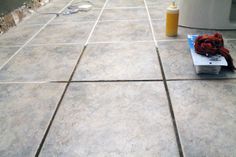 a pile of books sitting on top of a tile floor next to a trash can