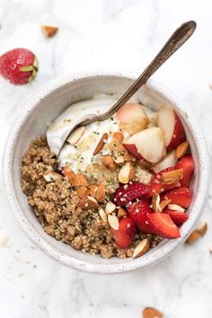 a bowl filled with granola, strawberries and yogurt next to a spoon