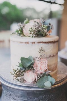 a wedding cake decorated with flowers and greenery