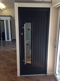 an empty room with a black door and wooden flooring on the other side of it