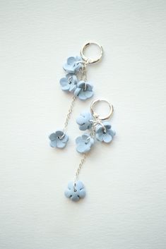 two key chains with blue flowers hanging from them on a white surface, one is attached to the other