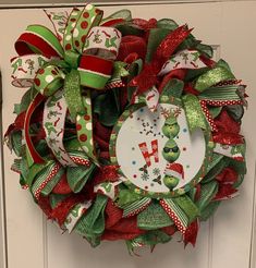 a green and red christmas wreath on a door with the letter f in it's center