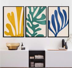 three paintings on the wall in a living room