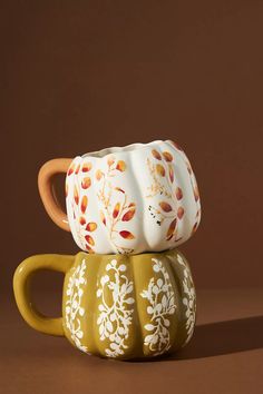 two coffee mugs sitting on top of each other in front of a brown background