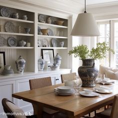 a dining room table with plates and vases on it