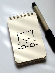 a notepad with a cat drawn on it next to a pen