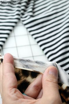 a person is sewing on a black and white striped shirt with her left hand holding the fabric