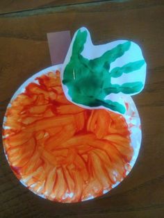 a paper plate with an orange and green handprint on it