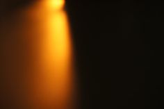 an orange light shines brightly on a black background with only one object visible in the foreground